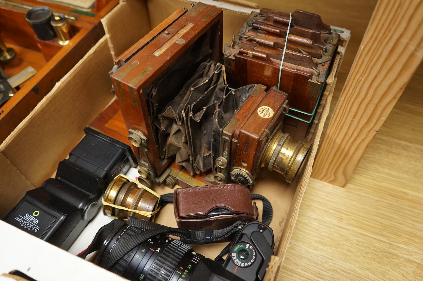 A Pentax P30 camera with Sunpak auto 2000DZ flash and instruction manual, together with an early 20th century mahogany cased quarter plate camera with accessories including lenses, a separate shutter unit, and four negat